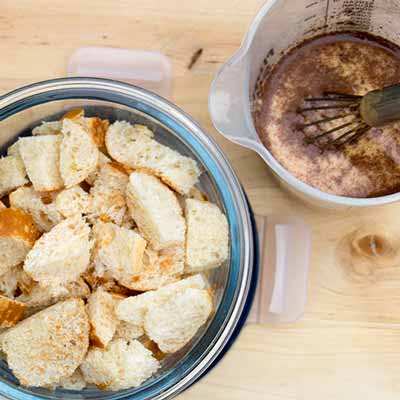 Das Eiergemisch und warme Milch &uuml;ber die Br&ouml;tchen geben